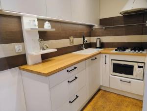Una cocina con gabinetes blancos, un fregadero y un microondas. en Apartament Cichy, en Poznan