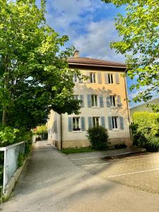 ein großes weißes Gebäude mit Bäumen davor in der Unterkunft Appartement in Couvet