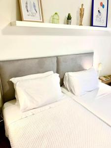 Una cama con sábanas blancas y almohadas. en Yellow Five Apartment, en Ponta Delgada
