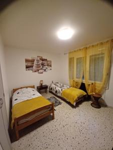 Dos camas en una habitación con cortinas amarillas. en La madeleine 1, en Caussade