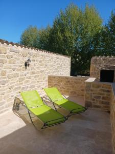 two green lounge chairs on a patio with a brick wall at La poumo d'amour in La Tour-dʼAigues