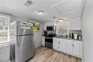 a kitchen with a stainless steel refrigerator and white cabinets at Downtown Cottage Hammond, Pool, Hot Tub, King Bed in Hammond +12 photos