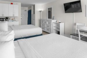 a white bedroom with two beds and a kitchen at Modern & Updated Oceanview Studio! Sleeps 4! Landmark 523 in Myrtle Beach
