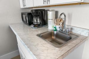 a kitchen counter with a sink and a microwave at Modern & Updated Oceanview Studio! Sleeps 4! Landmark 523 in Myrtle Beach