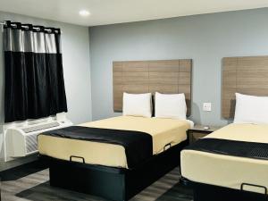 two beds in a small room with two beds sidx sidx sidx at EXPRESS INN & Suites in El Campo