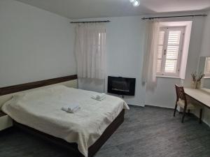a bedroom with a bed and a desk and a television at Rooms Dana Old Town Budva in Budva