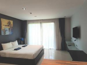 a bedroom with a bed and a large window at Emerald Terrace Condo 3-Studio Garden Gem in Patong Beach
