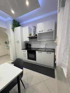 a kitchen with white cabinets and a sink and a table at L' Aurora Azzurra casa vacanze Casa Maria in Trecase