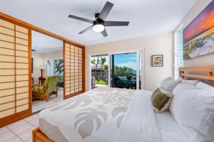 a bedroom with a bed with a fan and a balcony at Big Island Alii Villas 333 by Coldwell Banker Island Vacations in Kailua-Kona