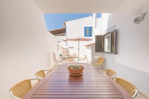 a dining room table with chairs and an umbrella at Milfontes Beach House in Vila Nova de Milfontes