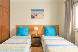 two beds in a room with blue pillows at Milfontes Beach House in Vila Nova de Milfontes