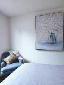 a bedroom with a blue chair and a painting on the wall at Your home away from home in Pickering +18 photos