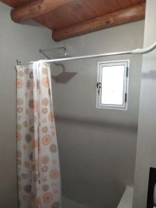 baño con cortina de ducha y ventana en Departamento Dharma, en Capilla del Monte