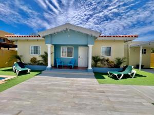 a house with two blue chairs in a yard at The Gold Vacation Villa in Santa Cruz
