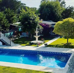 a swimming pool with a fountain in a yard at Margaritas y Soles Petit Hotel in San Miguel del Monte