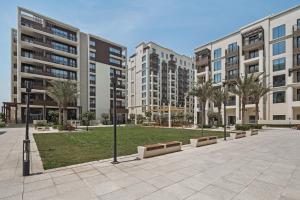 a park with palm trees and tall buildings at qua Serenity Poolside with Community Views in Dubai