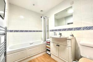 a white bathroom with a sink and a tub and a sink at 4-Bedroom Retreat in Staines with Private Garden & Easy Parking in Staines +15 photos