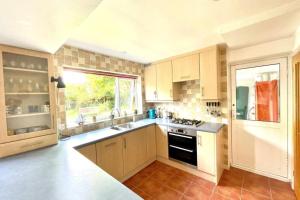 a kitchen with white cabinets and a sink and a window at 4-Bedroom Retreat in Staines with Private Garden & Easy Parking in Staines
