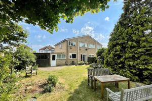 a house with a table and benches in the yard at 4-Bedroom Retreat in Staines with Private Garden & Easy Parking in Staines