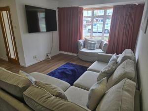 a living room with a couch and a tv at 4-Bedroom Retreat in Staines with Private Garden & Easy Parking in Staines