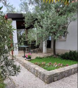 a garden in front of a house with a table and a tree at House Feniks, 2 bedrooms, private parking, Starlink! in Milna