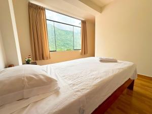 Un dormitorio con una cama grande con ventana. en Hospedaje Maranura Quillabamba, en Maranura