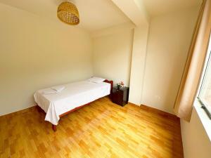 Un dormitorio con una cama blanca y suelo de madera. en Hospedaje Maranura Quillabamba, en Maranura