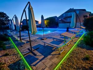 a pool with lounge chairs and umbrellas at night at Apartments Lea with pool in Malinska