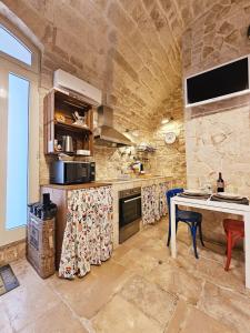 a kitchen with a table and a stone wall at Nilò holiday house in Molfetta +8 photos