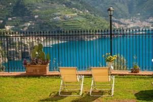 two chairs sitting in front of a fence with a lake at Villa Il Lupo Felice - Panoramic Sea View Villa, Ravello in Ravello