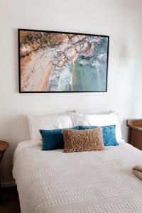 un dipinto è appeso sopra un letto con cuscini blu di Luxe Homestay 4 BEDROOM Option at 6 O'Clock Shadows a Orbost