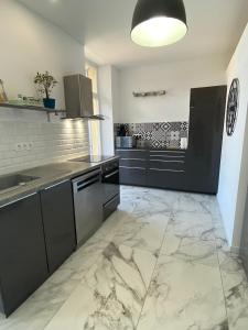 a kitchen with black cabinets and marble flooring at Casa Sanna, T2 waterfront Miomo, Cap Corse in Santa-Maria-di-Lota