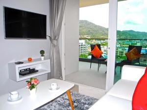 a living room with a couch and a tv and a balcony at Emerald Terrace Condo 9-1 Bed City & Mountain in Patong Beach