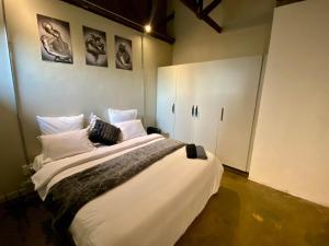 a bedroom with a large bed with white sheets and pillows at Arcade Art Loft in Johannesburg
