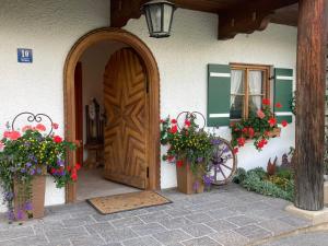 wejście do domu z drewnianymi drzwiami i kwiatami w obiekcie Oberstöberl w mieście Bischofswiesen