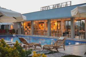 a swimming pool with two chairs and a building at La Vida otel in Urla