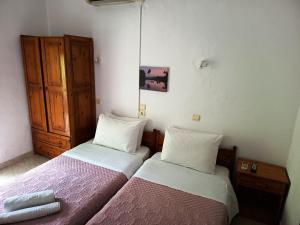a bedroom with two beds and a wooden cabinet at Eleni's Rooms in Samothraki