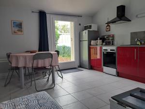 a kitchen with red cabinets and a table and a window at La Mignonnette in Grues