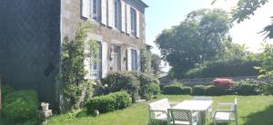 a table and chairs in front of a house at Family home Cour du Louvre in Saint-Sever-Calvados