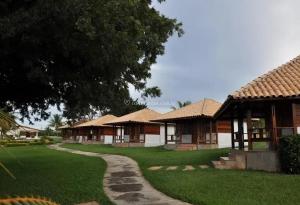 a row of cottages with a tree and a path at Resort Pedra do Sonho in Janaúba