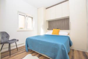 a bedroom with a blue bed and a chair at Apartments Capocesto in Primošten