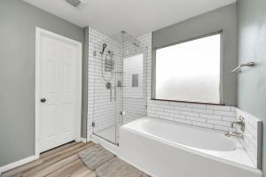 a white bathroom with a tub and a window at King Bed Private Bathroom.Fast Wi-fi.Projector in Katy +5 photos