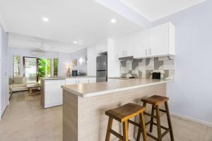 a kitchen with white cabinets and a counter with stools at The Queenslander - Full Moon Terrace in Port Douglas