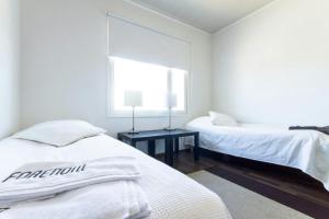 a white bedroom with two beds and a window at Spacious Apartment for 8 with Sauna in Kerava