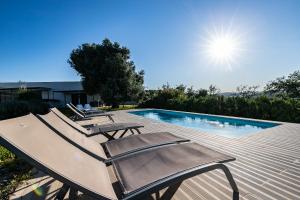 a swimming pool with two lounge chairs and the sun at Monte Oliva - Turismo Rural in Cerro da Zorra