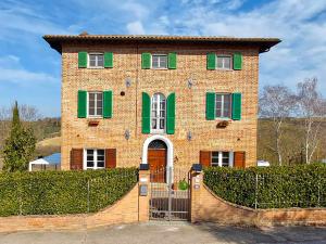 a brick house with green shutters and a gate at Dimora Gentile BnB in Castiglione del Lago