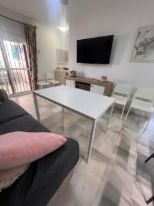 a living room with a white table and a tv at LAGUNA BEACH PISCINA- HOME RENt MALAGA in Torrox Costa
