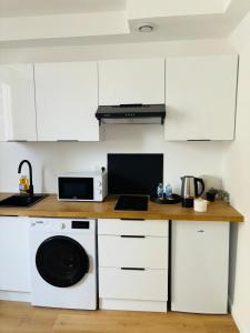 a kitchen with white cabinets and a counter with a dishwasher at Le 32 - Studio rénové - Centre in Coudekerque-Branche +9 photos