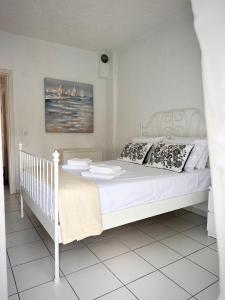 Una cama blanca con almohadas y un cuadro en la pared. en Pap's Summer House, en Polychrono