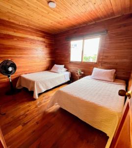 a bedroom with two beds in a wooden cabin at Cabaña Dulce Encanto in Villeta